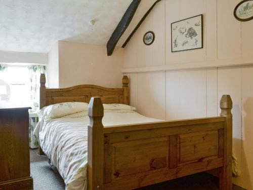Llanfaelrhys的住宿－Ty Hen，一间卧室配有一张木床和墙上的时钟