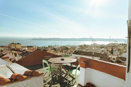 a table and chairs on a balcony with a view of a city at Olympo Shared flat with Amazing River view in Lisbon