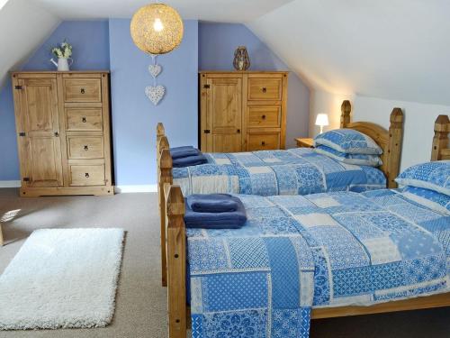 Duas camas num quarto com paredes azuis em Garden Cottage em Tain
