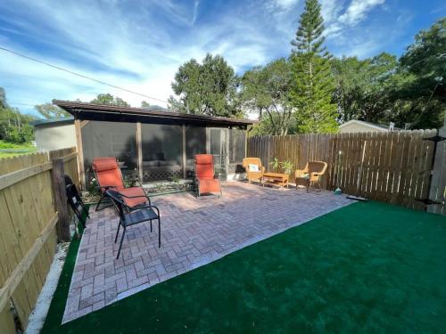 a backyard with a patio with orange chairs and a green lawn at Peaceful getaway and Explore Tampa in Oldsmar