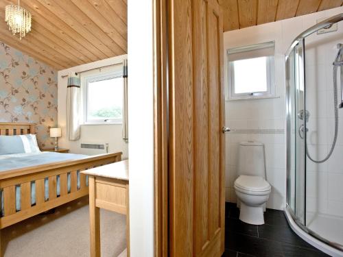 a bathroom with a bed and a shower and a toilet at Garfield Lodge in Hawkchurch