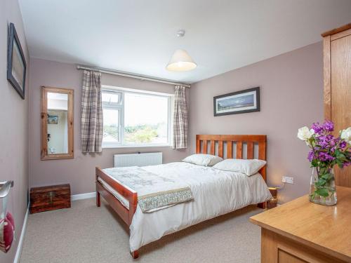 a bedroom with a bed and a vase of flowers at Driftwood Cottage in Galmpton-on-the-Dart