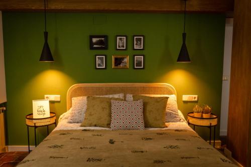 a bedroom with green walls and a bed with two end tables at Cuencaloft Casa S-XVII "La Catedral" in Cuenca