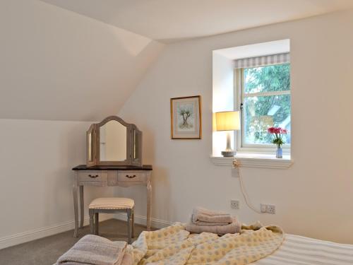 a bedroom with a bed and a table and a window at St Ronans Place in Gartocharn