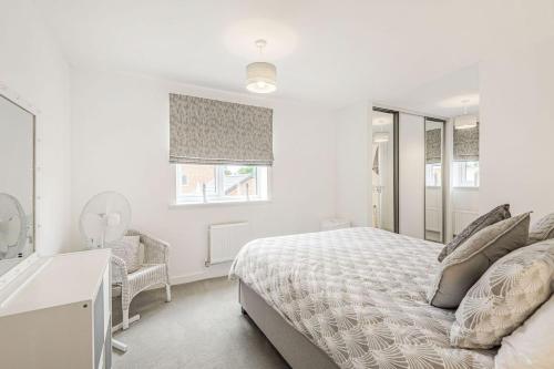a white bedroom with a bed and a mirror at Roma in North Walsham
