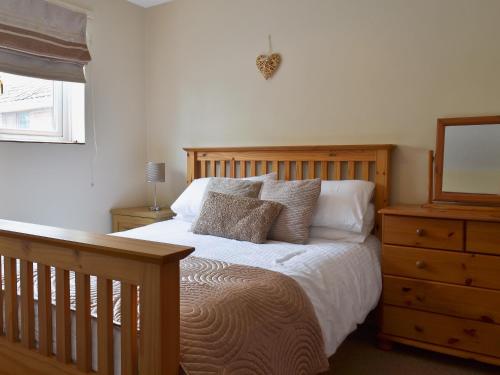 a bedroom with a bed and a dresser with a mirror at Sycamore Cottage in Cote