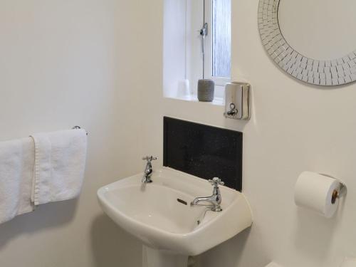 a white bathroom with a sink and a mirror at Robins Nest in Broomhill