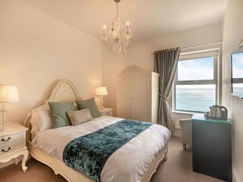 a bedroom with a bed with a chandelier and a window at Babbacombe House in Torquay