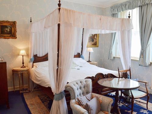 una camera con letto a baldacchino e tavolo e sedie di The Savoy a Buxton