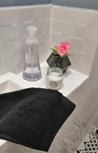 - un lavabo avec une serviette noire et une rose rose dans l'établissement Les Bichettes, à Mortagne-sur-Sèvre