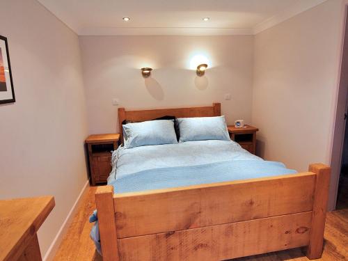 a bedroom with a wooden bed with blue pillows at Bryn Menai - Hw7573 in Llanddeiniolen