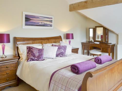 a bedroom with a large bed with purple pillows at Portington Lodge in Eastrington