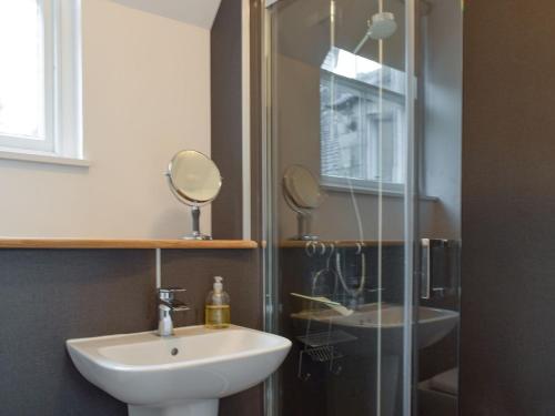 a bathroom with a sink and a glass shower at Coachmans Cottage in Falkland
