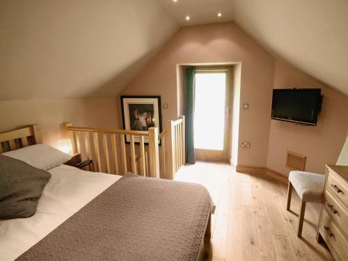 a bedroom with a bed and a television on the wall at Cornstore Cottage in Highpeak Junction