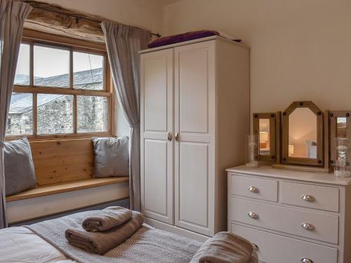 a bedroom with a bed and a dresser and a mirror at Beck Foot Cottage in Sedbergh