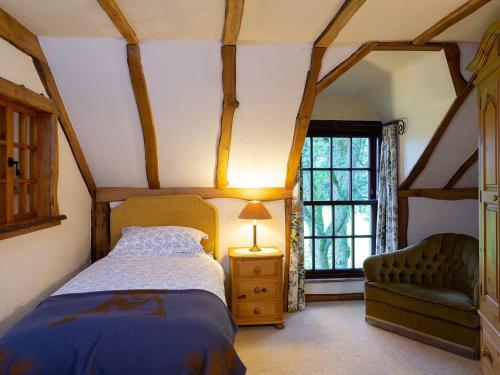 a bedroom with a bed and a chair and a window at The Hayloft in Milnathort