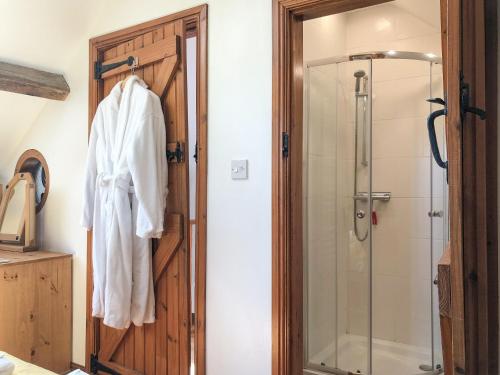 a bathroom with a shower and a robe hanging on a door at Tawny Owl Barn in Barlow