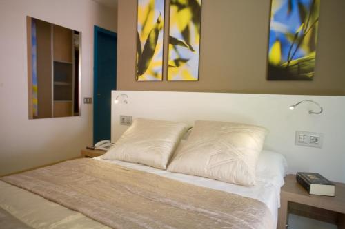 a bed in a bedroom with two paintings on the wall at Hotel La Sèquia Molinar in Campdevánol