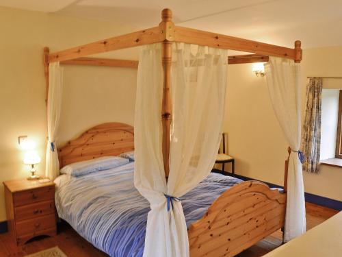 a bedroom with a wooden canopy bed with curtains at Blackberie Cottage - E2389 in Stoke Abbott