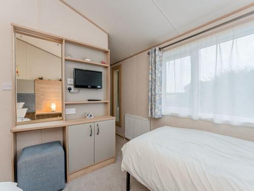 a bedroom with a bed and a tv and a window at Cledan in Llanon