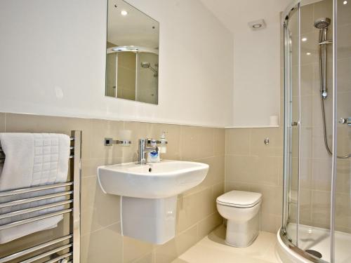 a bathroom with a sink and a toilet and a mirror at Una Aurum 56 in Carbis Bay