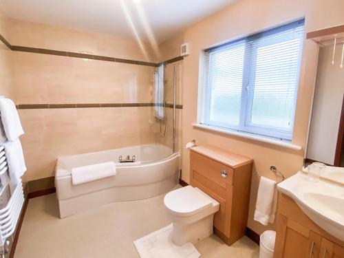 a bathroom with a tub and a toilet and a sink at Friarystone Cottage in Bamburgh