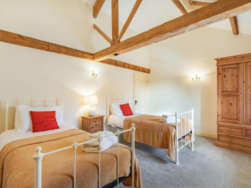 two beds in a room with wooden ceilings at The Grainery - Uk37516 in Routh