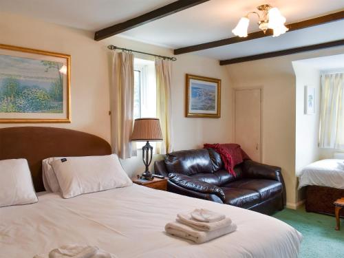 a bedroom with a bed and a leather couch at Alderley House in Bourton on the Water