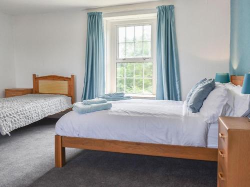 um quarto com 2 camas e uma janela com cortinas azuis em Laurel Farm em Rolstone