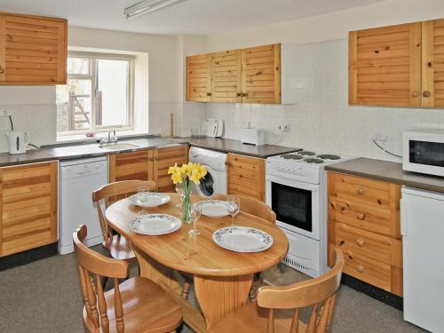 eine Küche mit einem Holztisch mit Stühlen und einem Esszimmer in der Unterkunft Maxmills Cottage - E1852 in Banwell