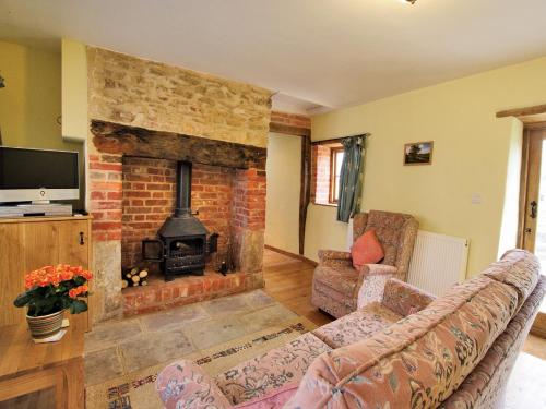 a living room with a brick fireplace and a couch at The Brewhouse in Foxham