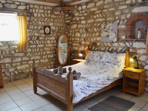 a bedroom with a bed and a stone wall at Guillemot Cottage in Flamborough