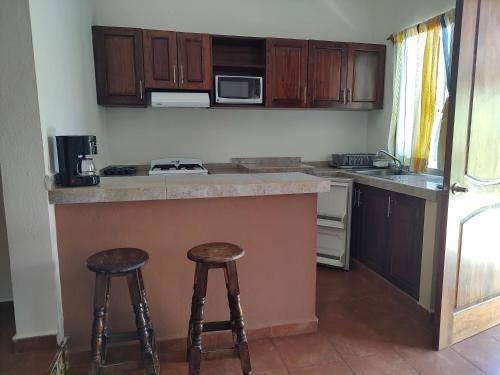 a kitchen with a counter and two stools in it at Villas victoria mirador in Zihuatanejo