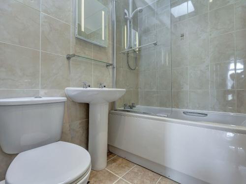 a bathroom with a toilet and a sink and a tub at 6 Torwood Gables in Torquay