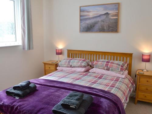 a bedroom with a bed with a purple blanket and two lamps at The Old Parish Hall in Seahouses