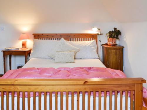 una camera da letto con un grande letto in legno con lenzuola rosa di The Aul Bank a Whitehills