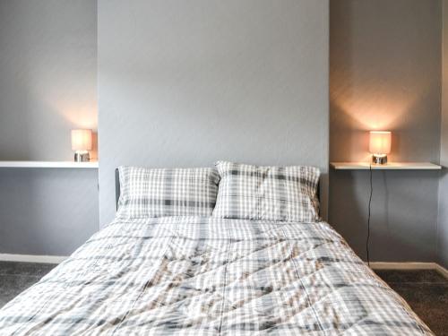 a bedroom with a bed with a plaid blanket and two lamps at White Rose Apartment in Bridlington