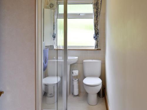 a bathroom with a toilet and a sink and a window at Cuillin View in Husabost