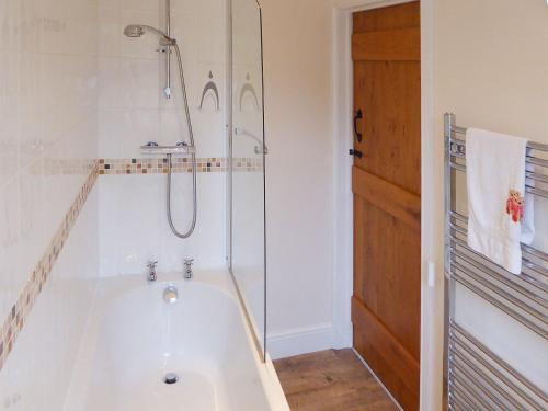 a white bathroom with a shower and a tub at Tuppence Cottage in Dulverton