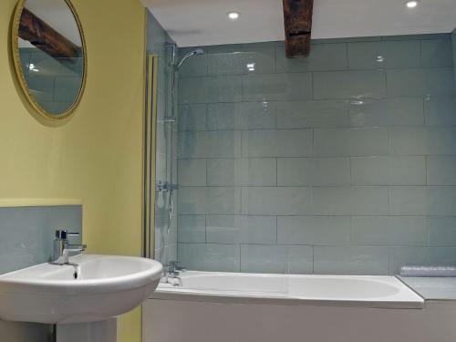 a bathroom with a sink and a tub and a mirror at Waxwing Cottage in Foxton