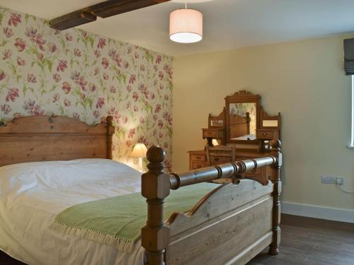 a bedroom with a bed and a dresser and a mirror at Waxwing Cottage in Foxton