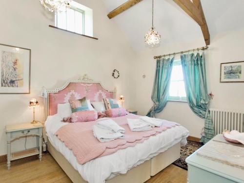 a bedroom with a pink and white bed with blue curtains at Old Reading Room in Osmotherley