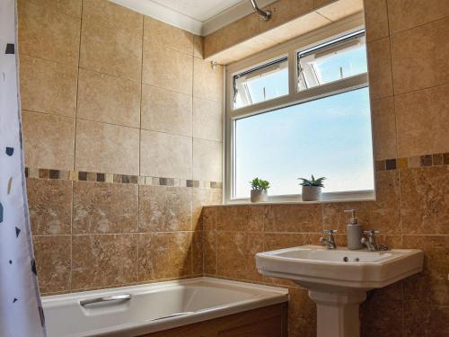 uma casa de banho com um lavatório, uma banheira e uma janela em Ocean View Cottage em Burry Port