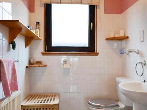 a bathroom with a toilet and a sink and a window at Sealladh Lingeigh in Pollachar
