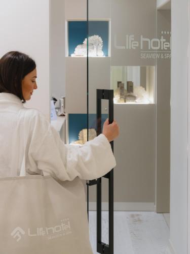 a woman standing in front of a glass display case at Life Hotel Seaview & Spa in Porto Recanati