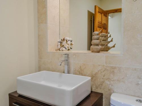 a bathroom with a white sink and a mirror at Seaviews And Hot Tub At The Fairways - Uk39821 in Portpatrick