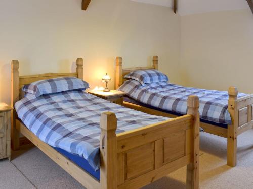 two twin beds in a room with two tables at Beckaveans Granary in Jacobstow