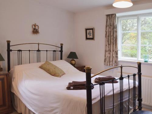 a bedroom with a bed with white sheets and a window at Apple Tree Cottage in West Wittering