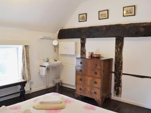 a bedroom with a bed and a sink and a dresser at Apple Tree Cottage in West Wittering