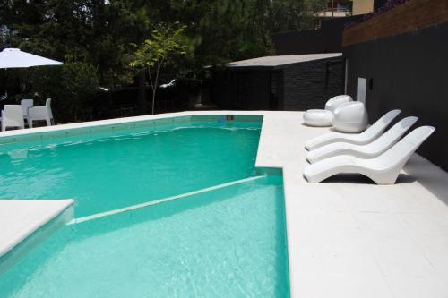 una piscina con dos sillas blancas sentadas al lado en Hotel Terrazas by CPH en Villa Carlos Paz